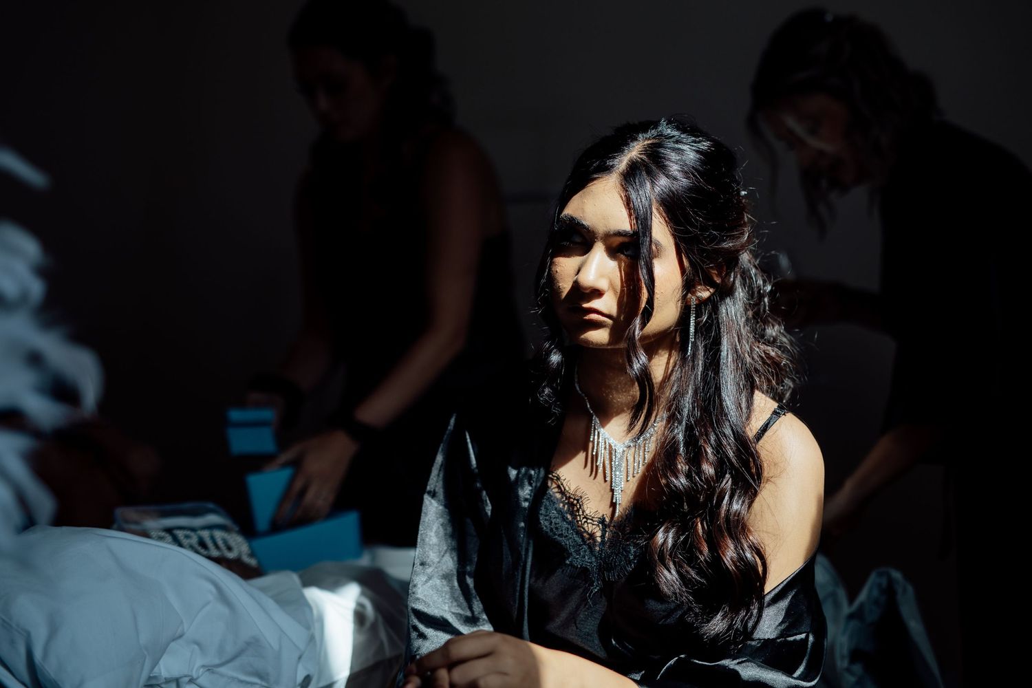 Candid getting-ready moment in dramatic lighting with long dark hair and black robe.