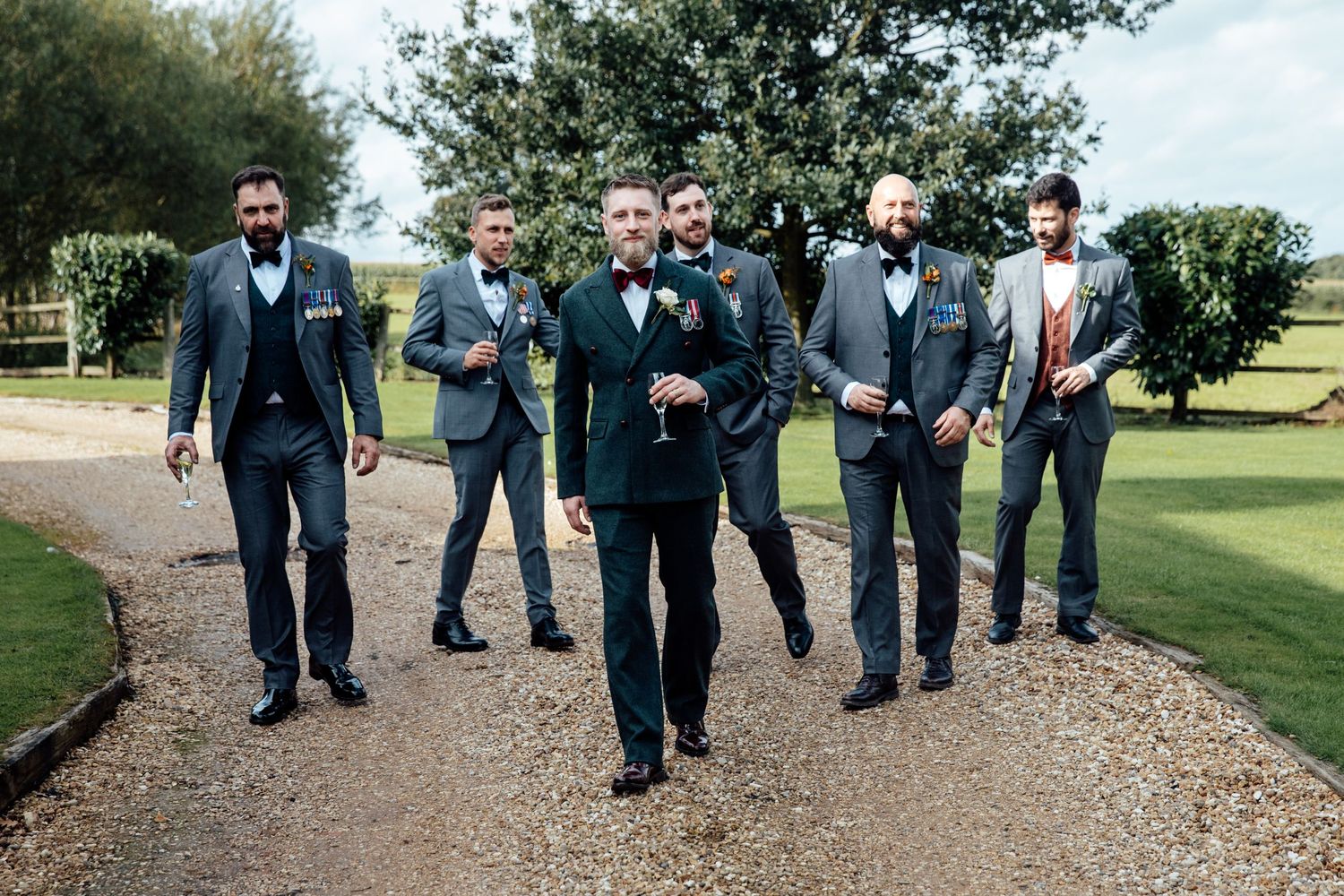 Wedding party walking together on a gravel path surrounded by greenery.