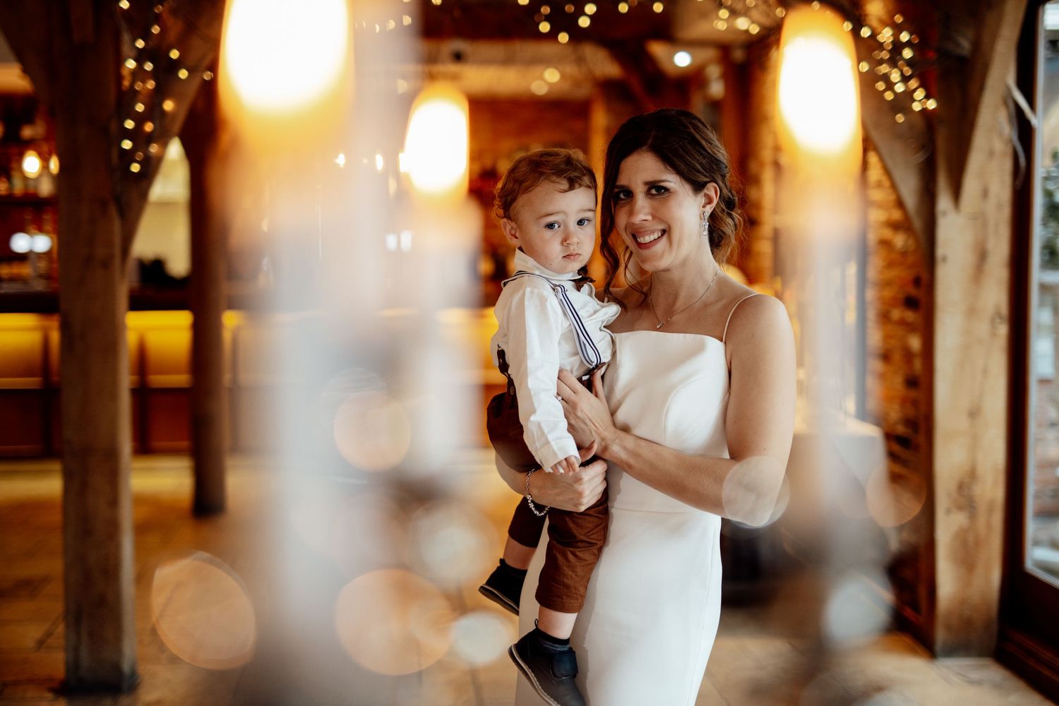 Wedding reception venue decorated with warm glowing string lights and rustic wooden beams.