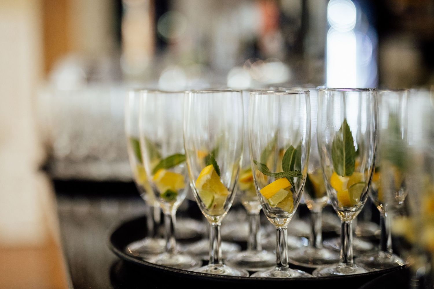 Row of champagne flutes garnished with fresh citrus slices on serving tray.