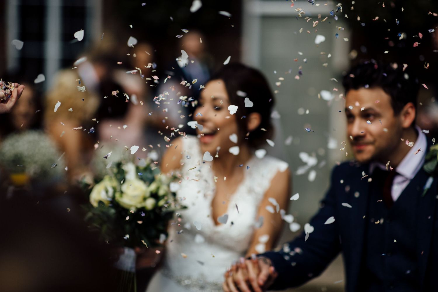 Joyful wedding celebration with confetti shower in dramatic black and white.