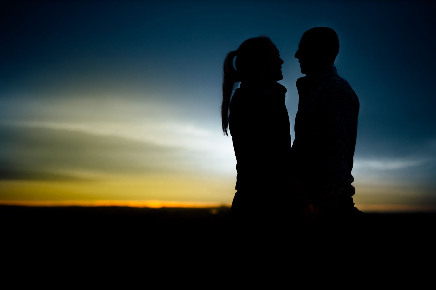 Silhouettes against a dramatic sunset sky with deep blue and orange hues.