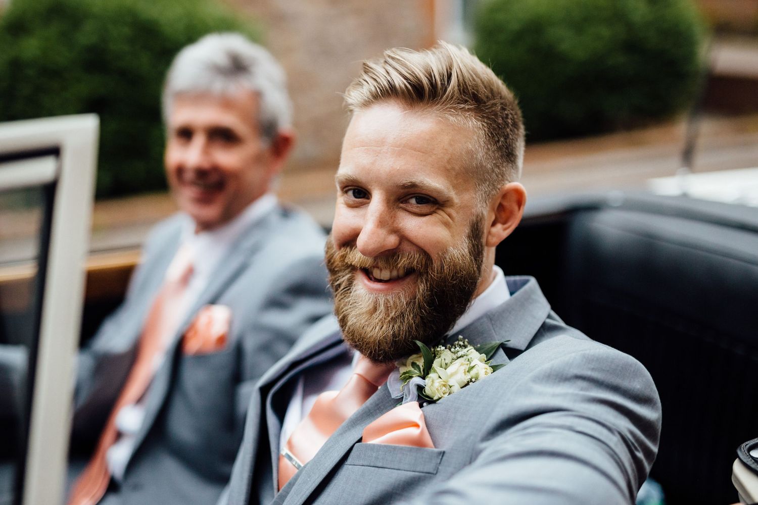 Wedding party in gray suits posing outdoors on a sunny day.