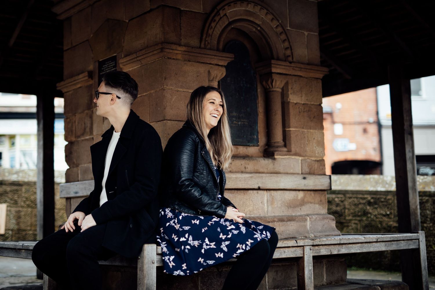 Couple standing beneath stone archway during intimate outdoor photoshoot.