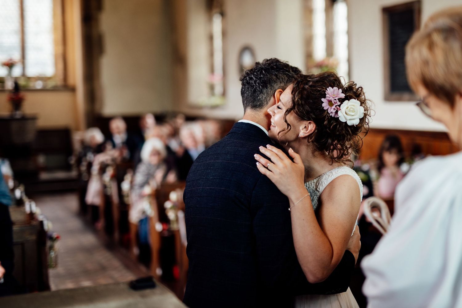 Intimate moment during a church wedding ceremony with guests seated in wooden pews.