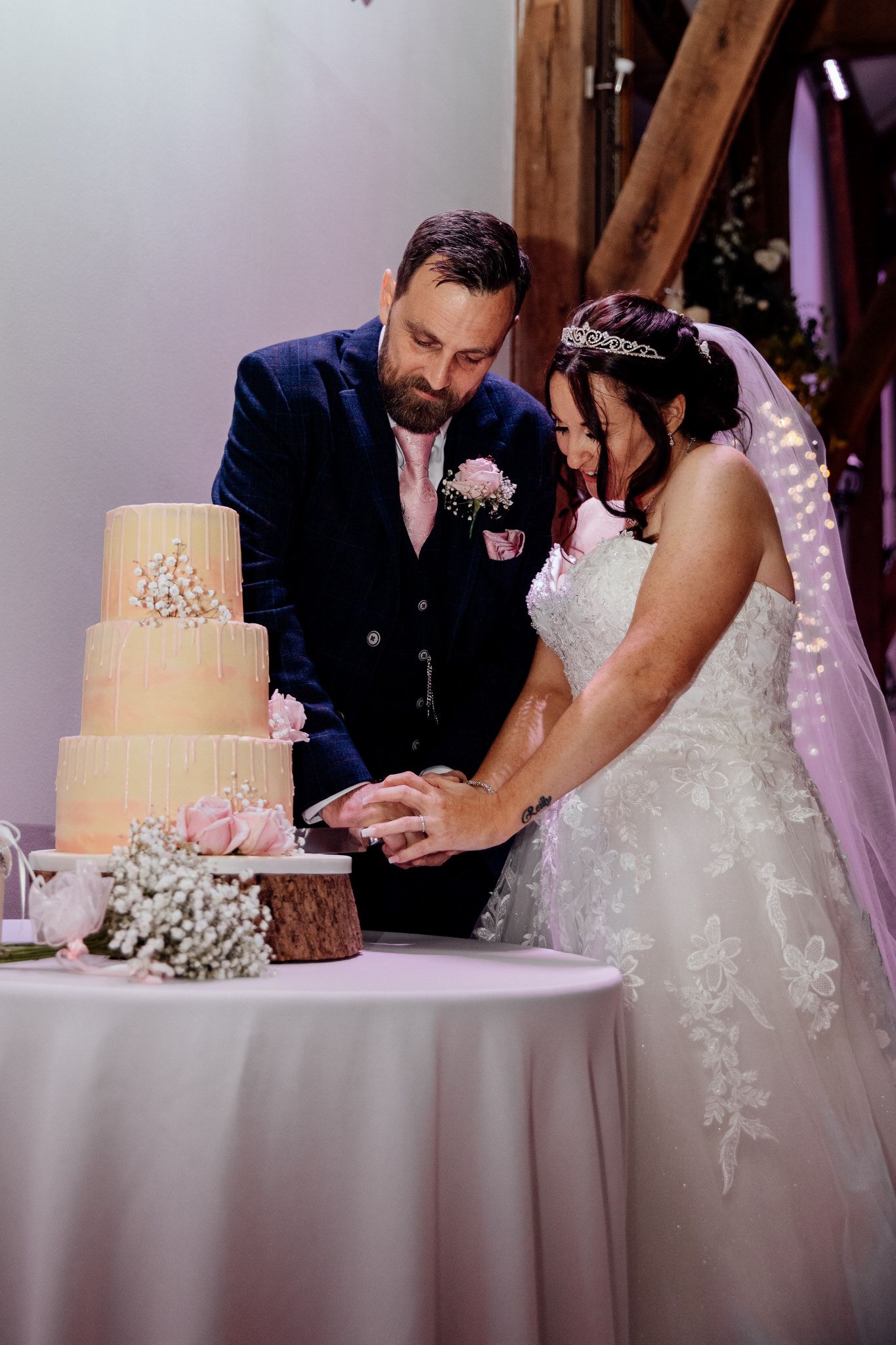 Newlyweds cut their elegant three-tiered wedding cake together at reception.
