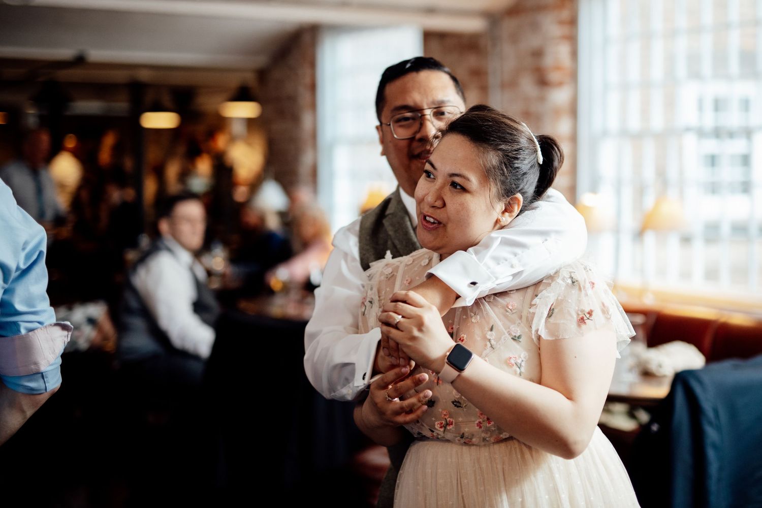 Wedding celebration in an industrial-style venue with brick walls and large windows.
