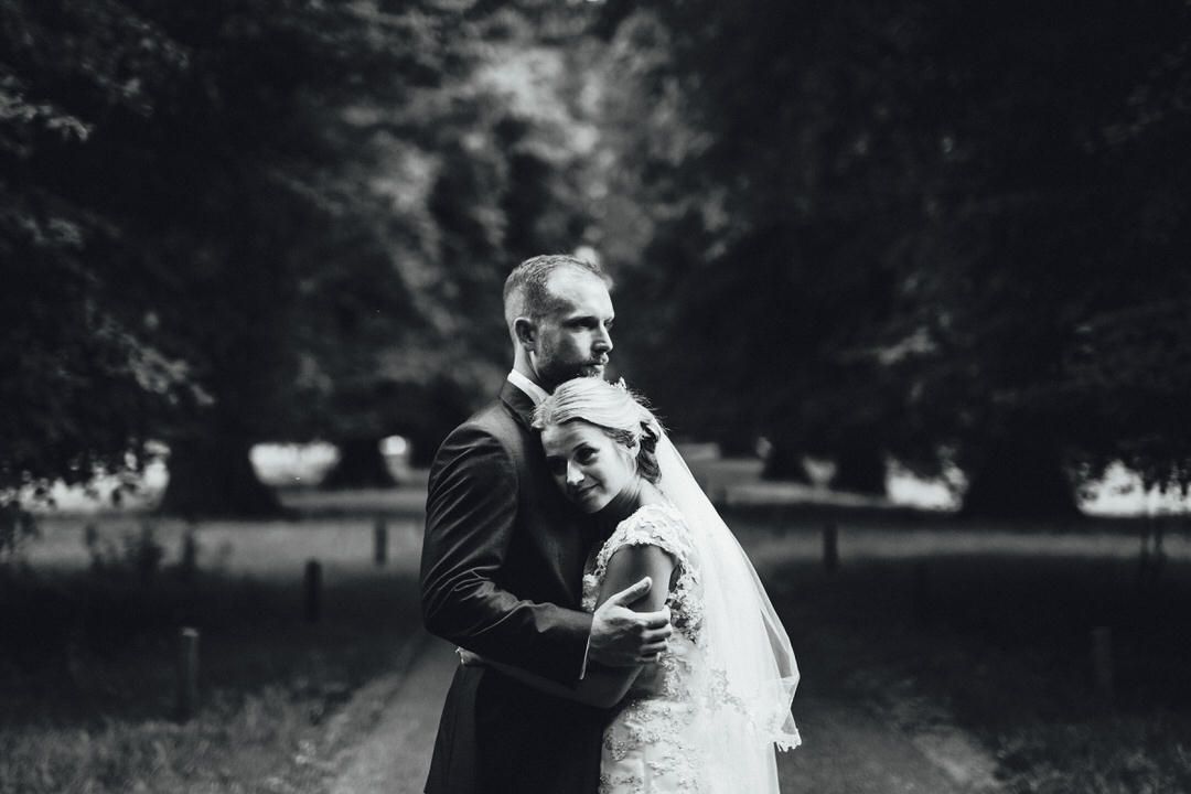 A black and white romantic moment captured in an outdoor garden setting.