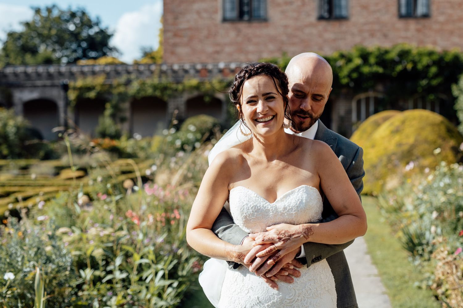 Couple sharing intimate moments in front of a rustic brick building with gardens.