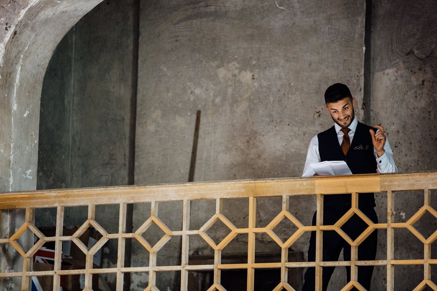 Musicians perform on a balcony overlooking a wedding reception in a historic brick venue.
