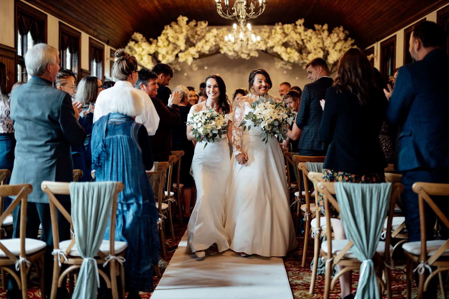 Indoor wedding reception with elegant chandelier and light blue bridesmaid dresses.