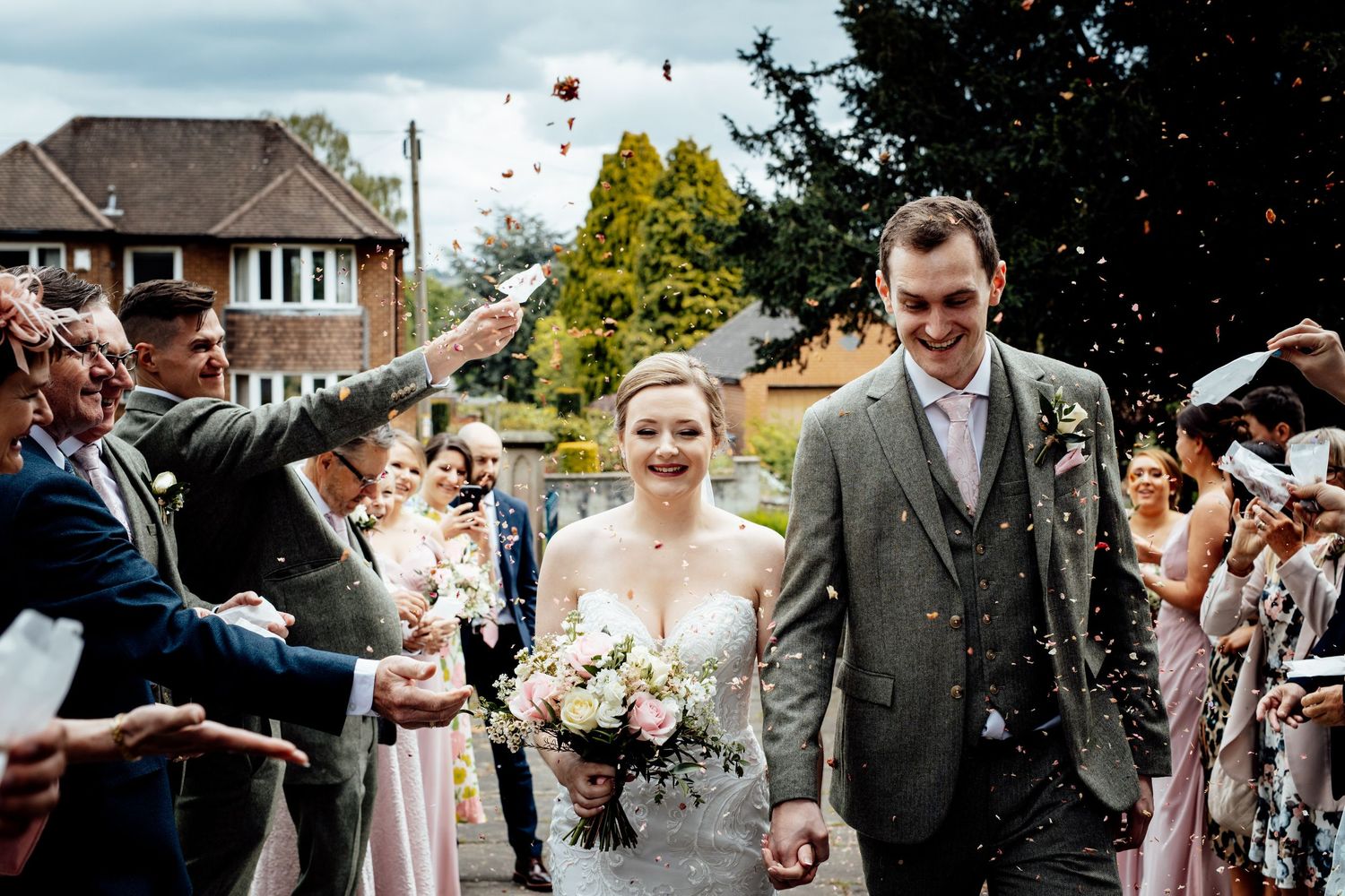 Wedding guests toss confetti and celebrate during an outdoor ceremony.