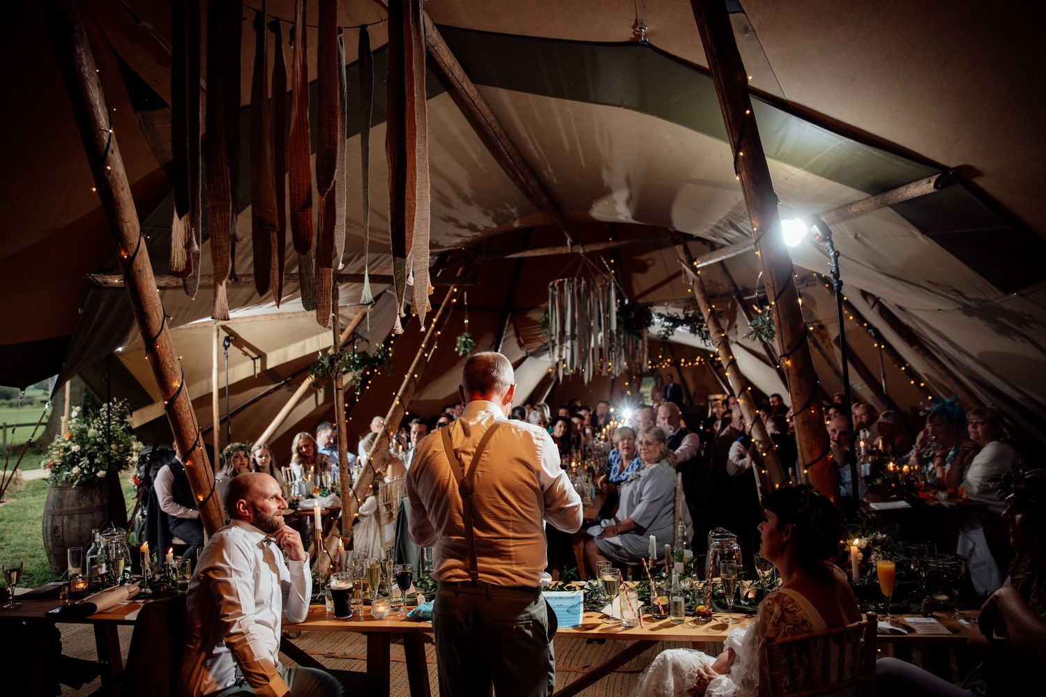 Evening wedding reception in a rustic barn venue with ambient lighting.