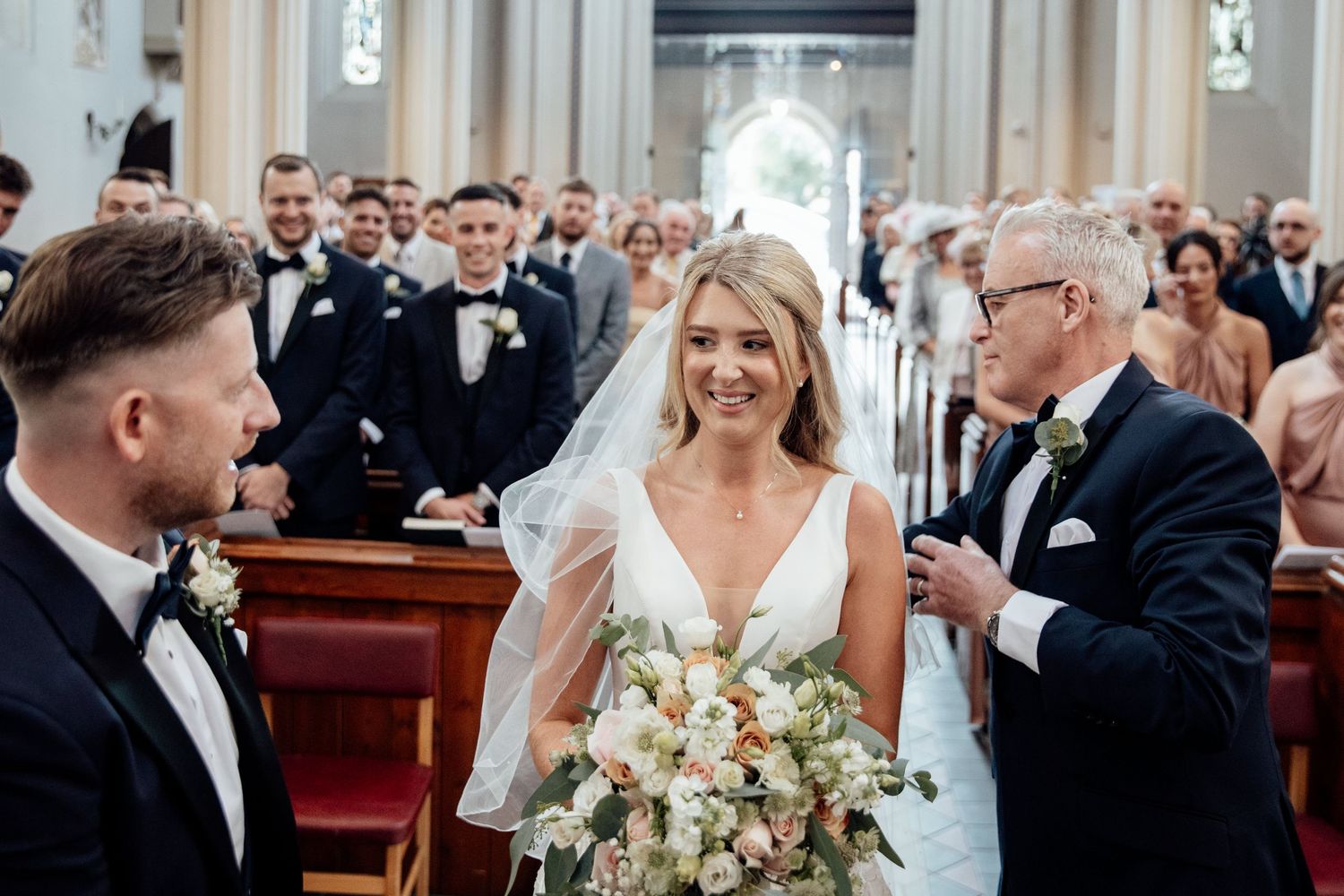 Traditional church wedding ceremony with elegant floral arrangements and wooden pews.