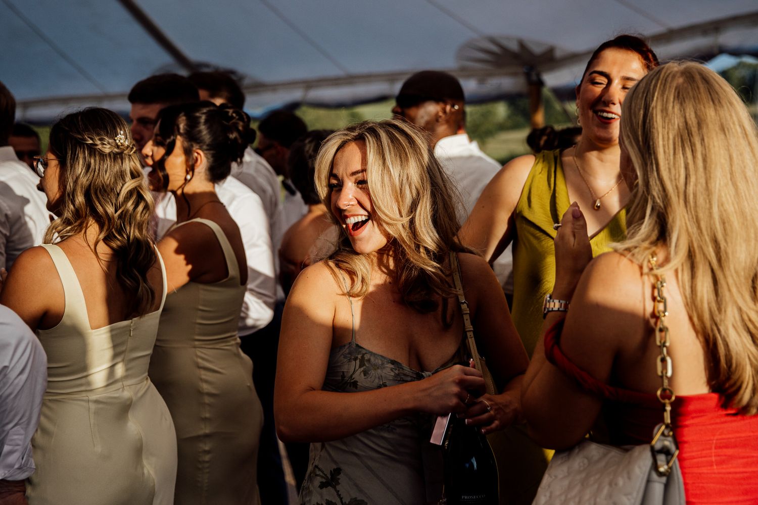 Wedding guests dancing and socializing at an outdoor reception during golden hour.