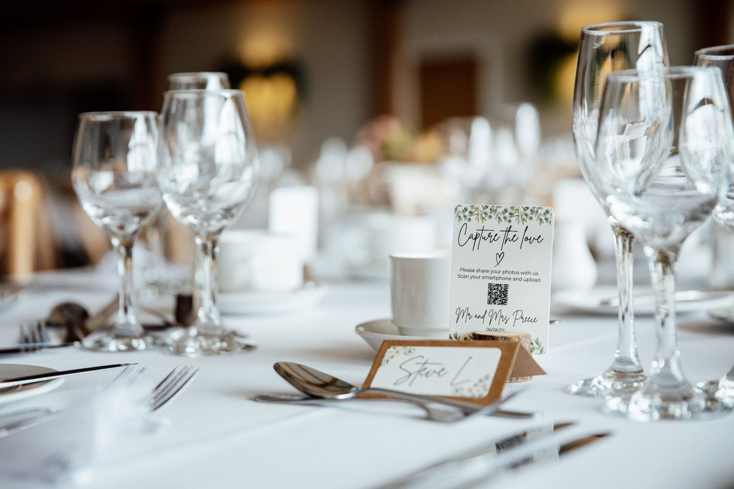An elegant table setting with wine glasses and place cards for a wedding reception.