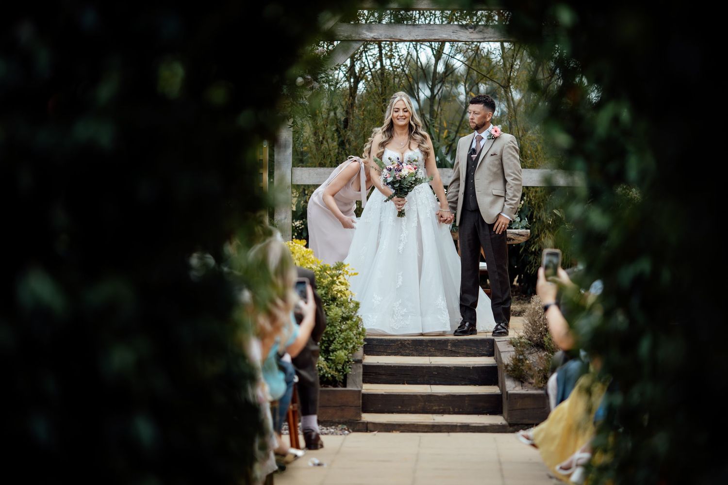 Bride and groom descend garden steps as guests toss confetti at their outdoor wedding ceremony.