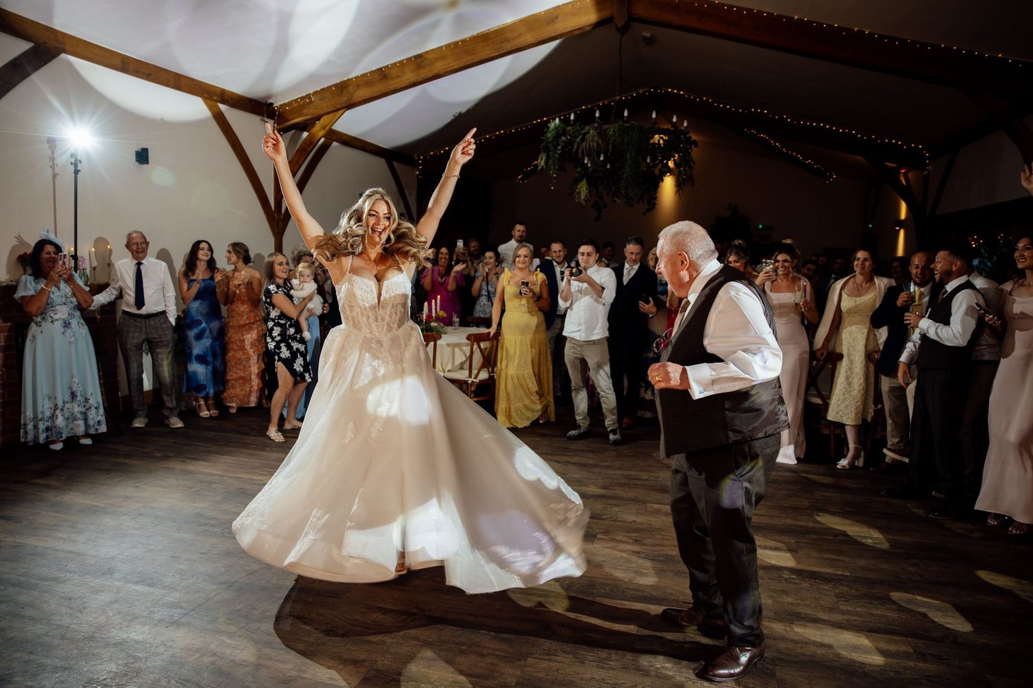 Bride dances joyfully with elderly guest on the dance floor at wedding reception.