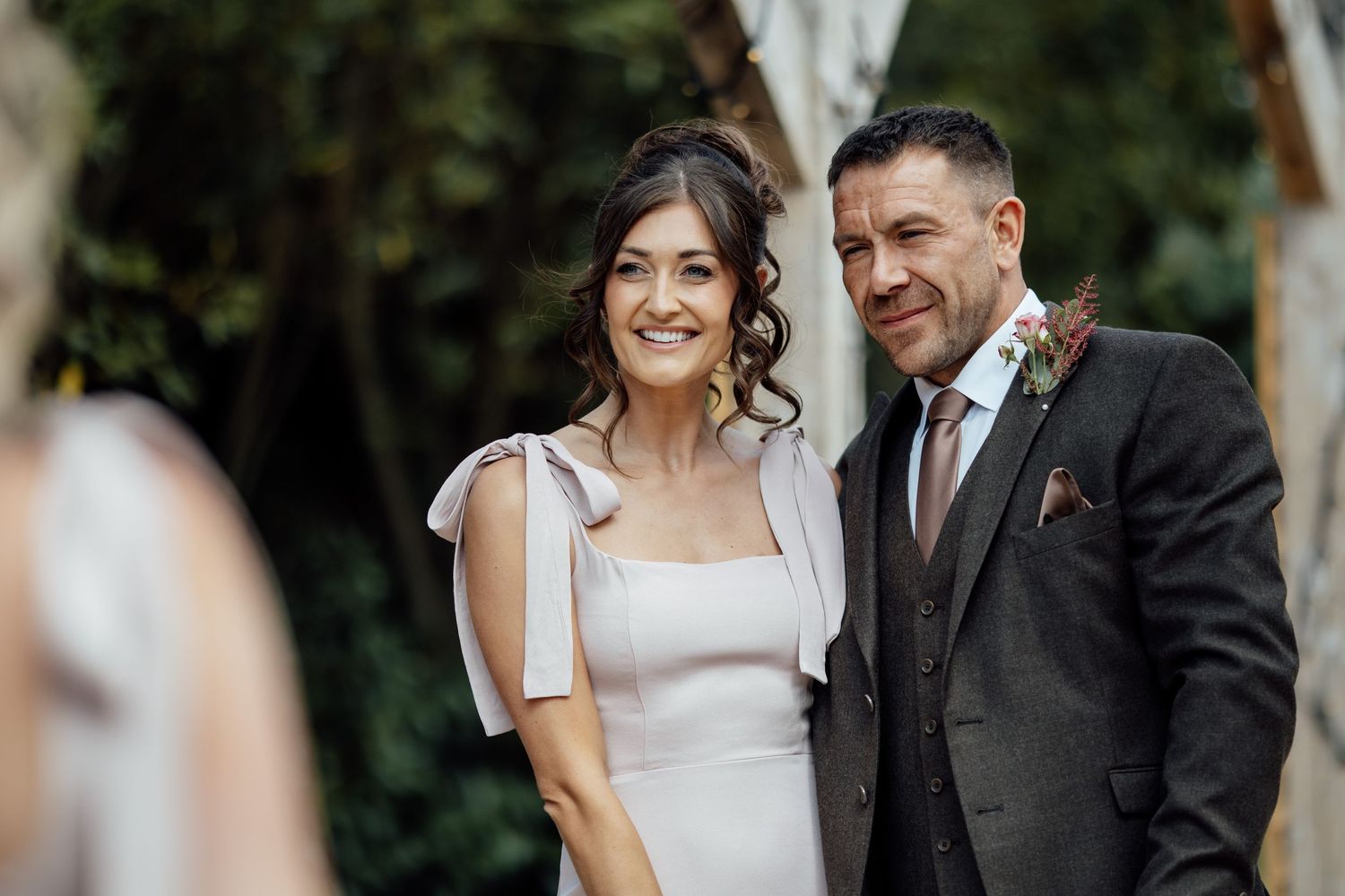 Smiling bride and groom pose together outdoors during their elegant autumn wedding celebration.