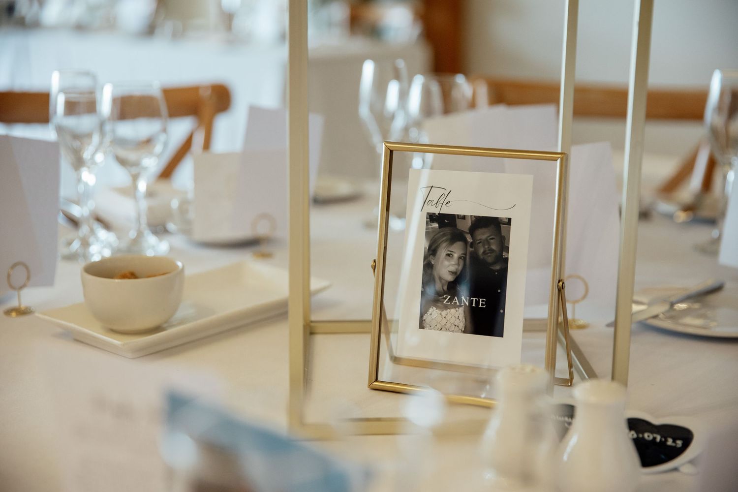 Elegant table settings with gold lantern centerpieces at a wedding reception.