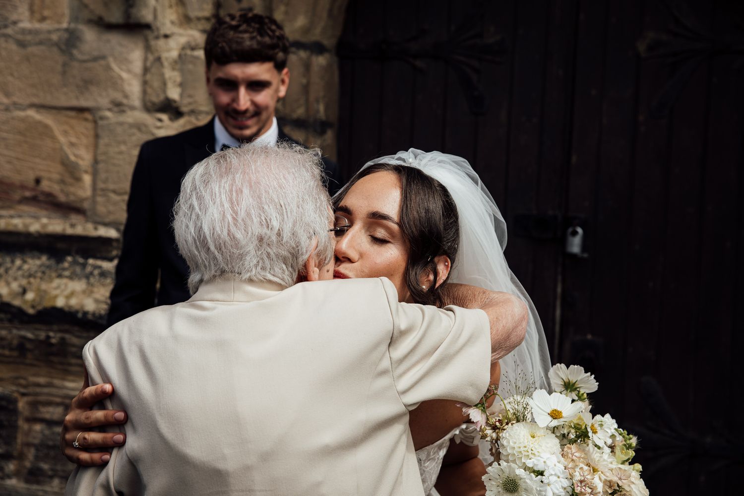 Intimate wedding moments captured against stone architecture backdrop.
