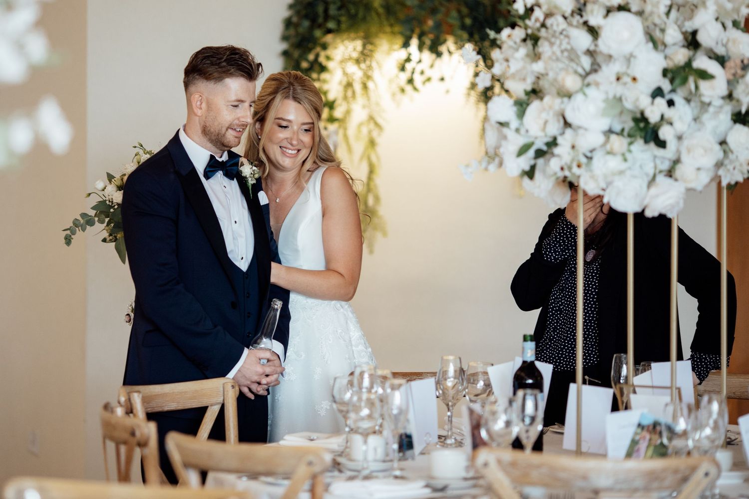 Elegant wedding reception setup with white floral arrangements and romantic lighting.
