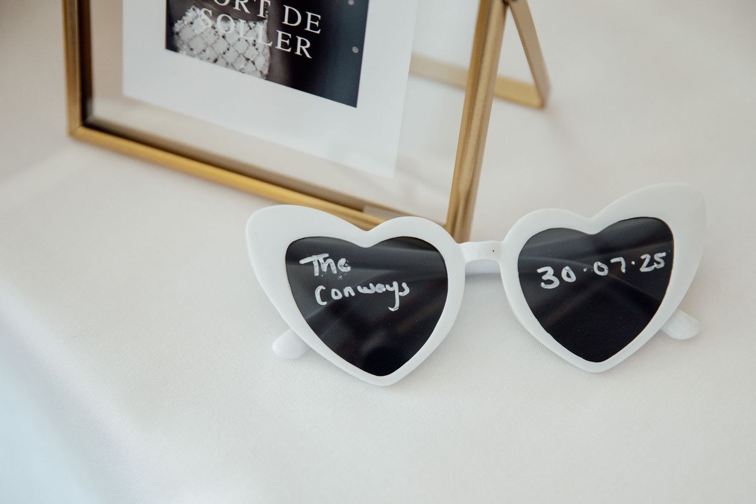 Heart-shaped chalkboard signs and wedding decor details on white surface.