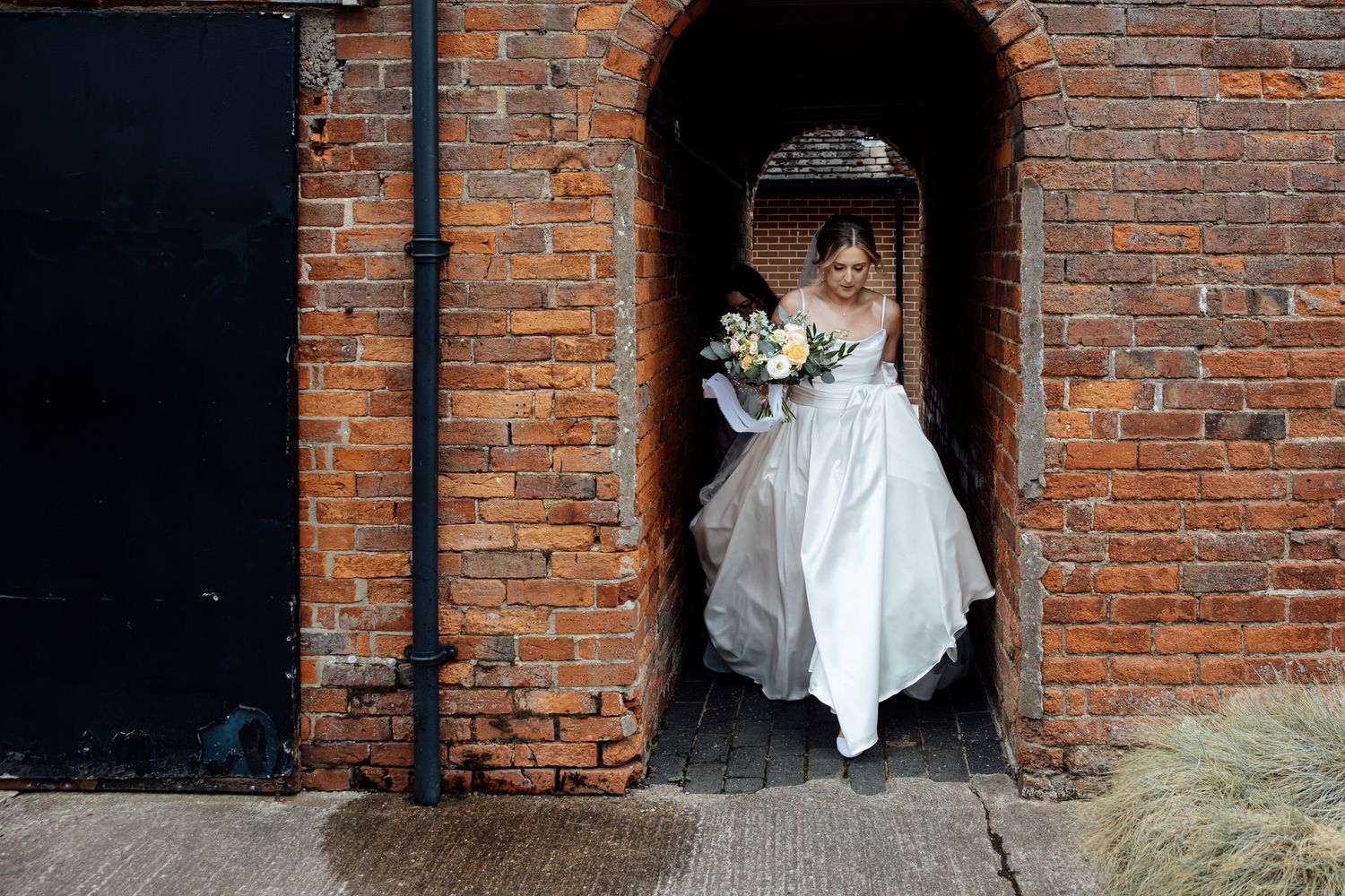 Wedding party posing against rustic brick wall backdrop.