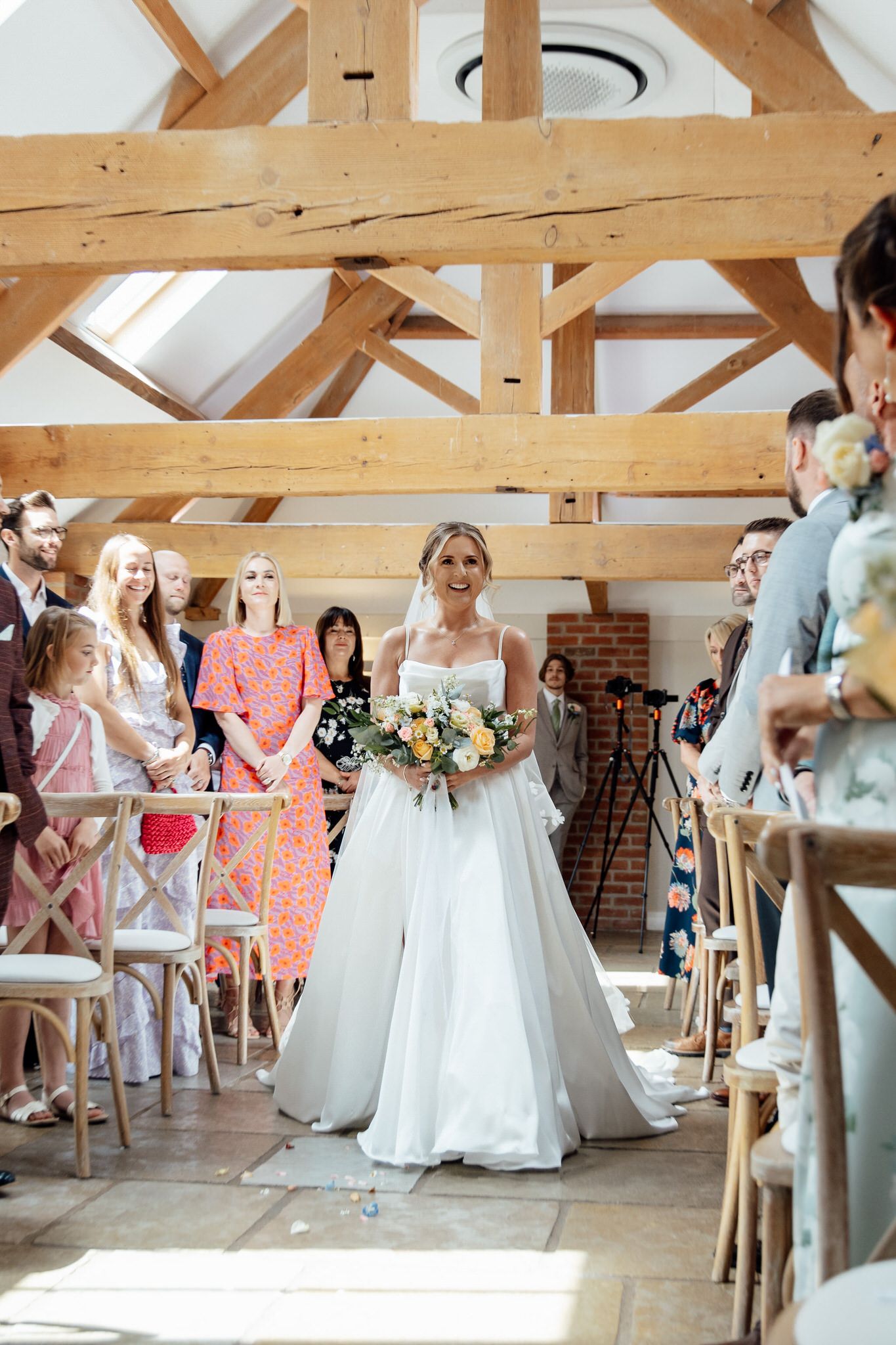 A wedding ceremony in a rustic venue with exposed wooden beams and natural lighting.