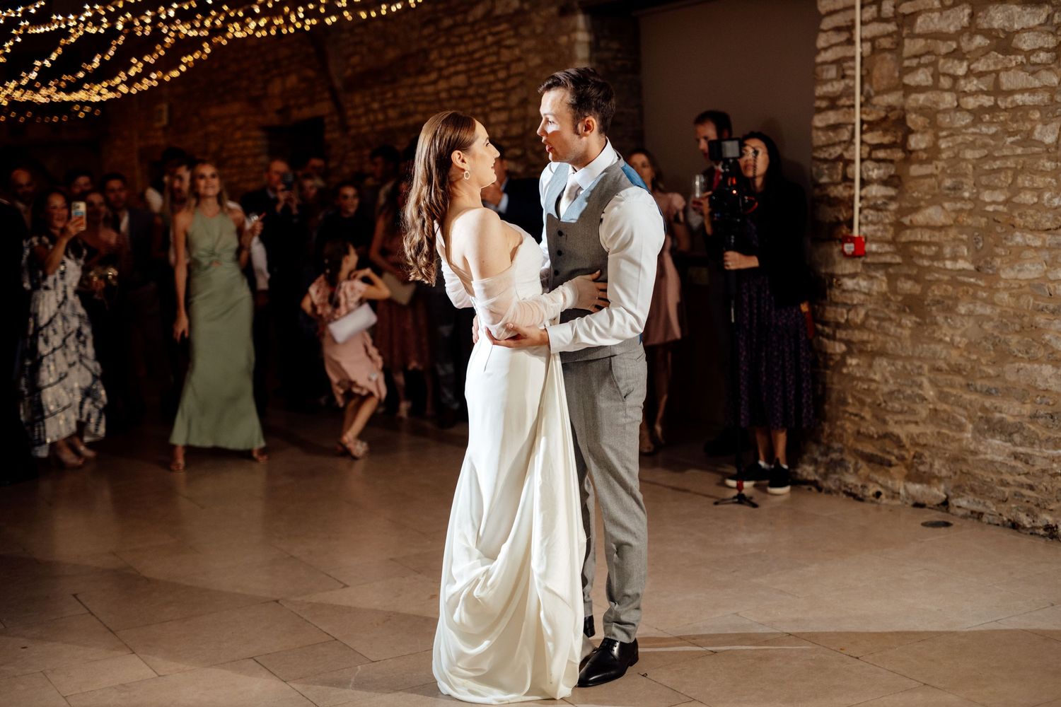 Wedding reception dance floor with string lights and exposed brick walls.