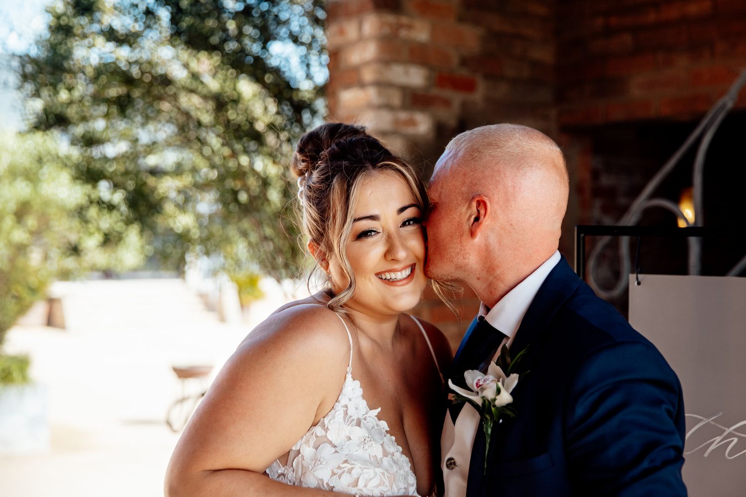 Romantic wedding portraits against rustic brick backdrop outdoors.