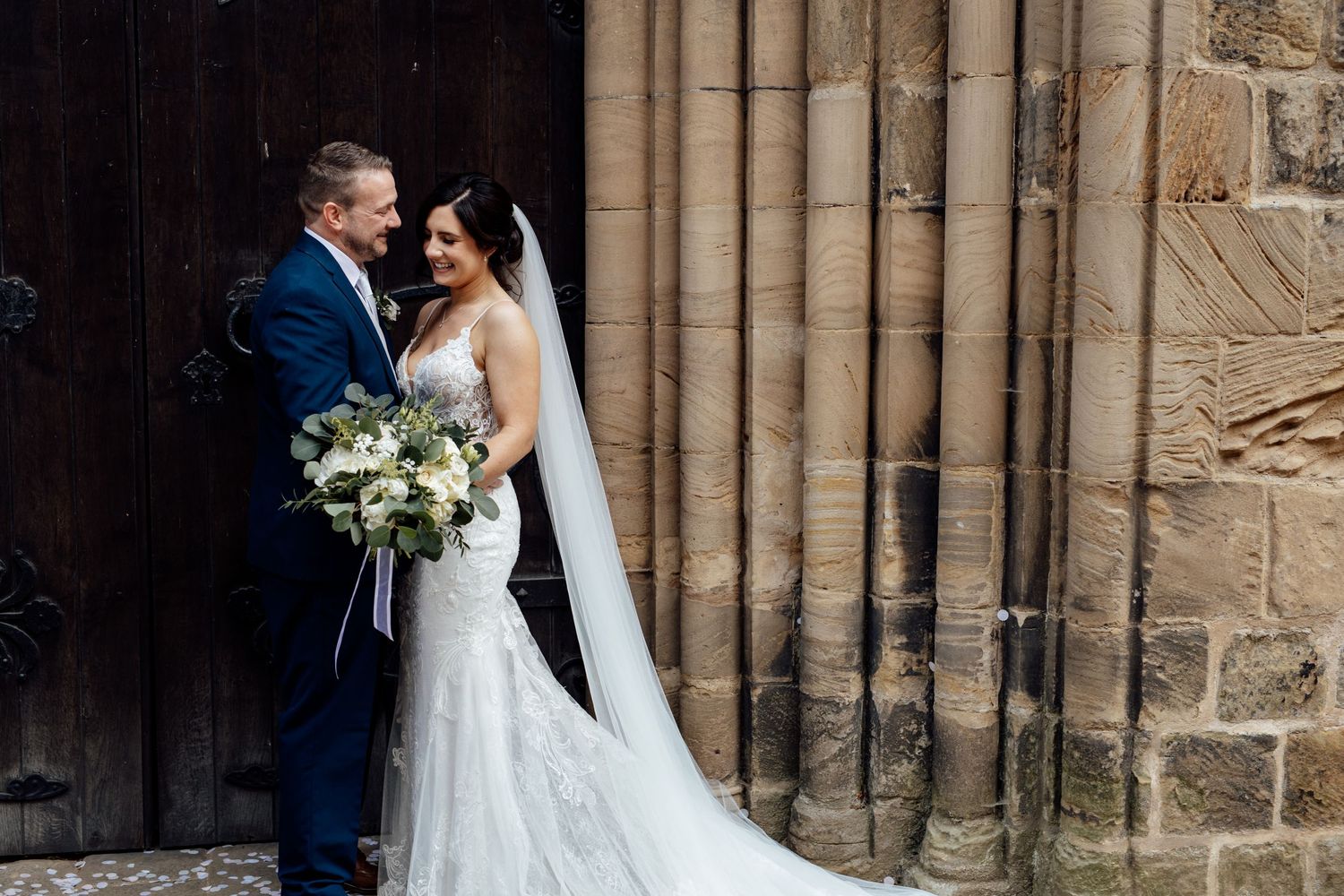 Wedding ceremony moments captured in front of historic stone church architecture.