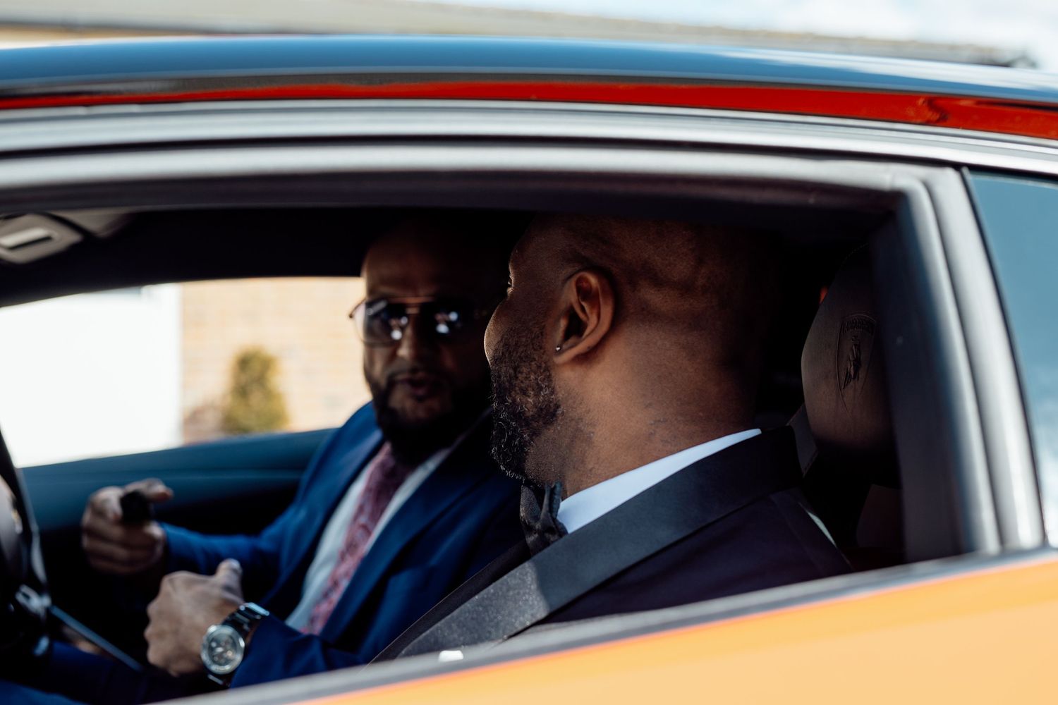 Two people in formal attire seated in a car before the wedding ceremony.