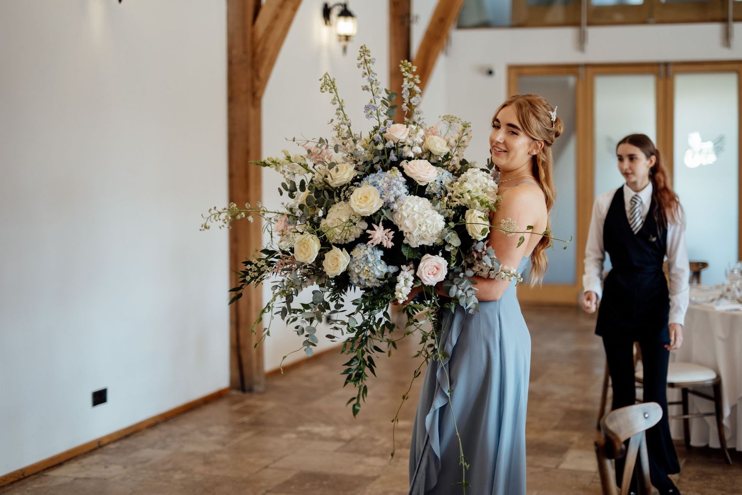 Large floral arrangement with white roses and greenery in an elegant barn venue.