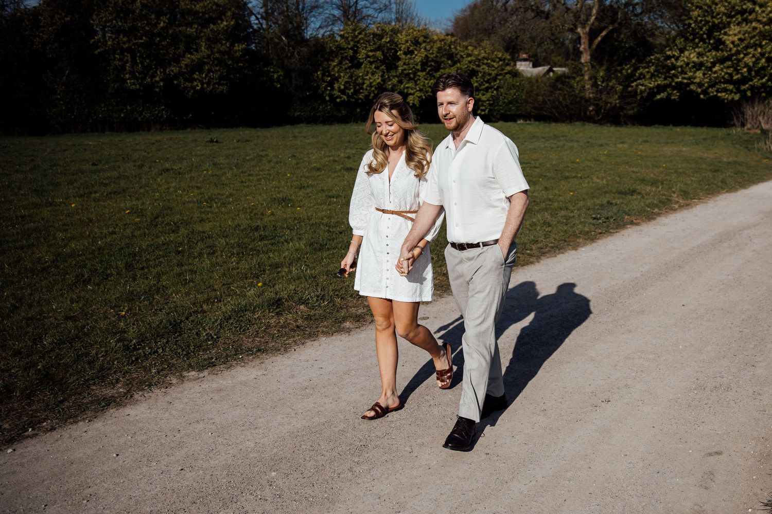 Two people walking together on a winding country path during a sunny afternoon.