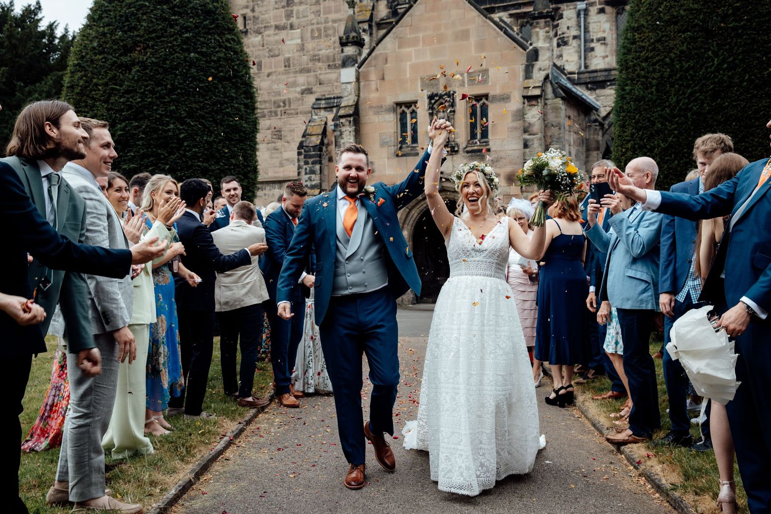 Wedding party and guests lined up outside historic stone building for celebration exit.
