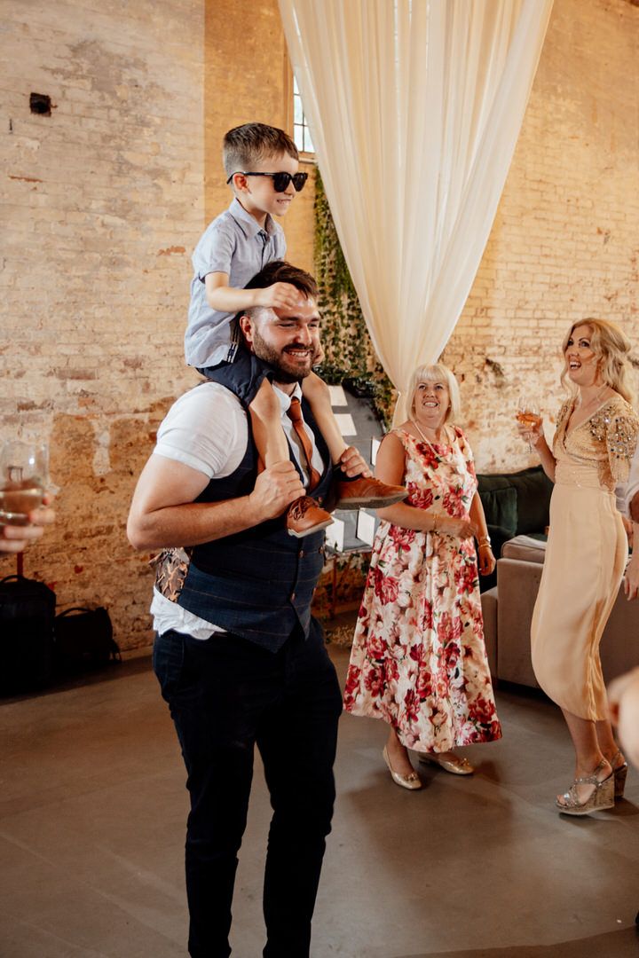 Guest dances enthusiastically at wedding reception in rustic brick venue with white draping.
