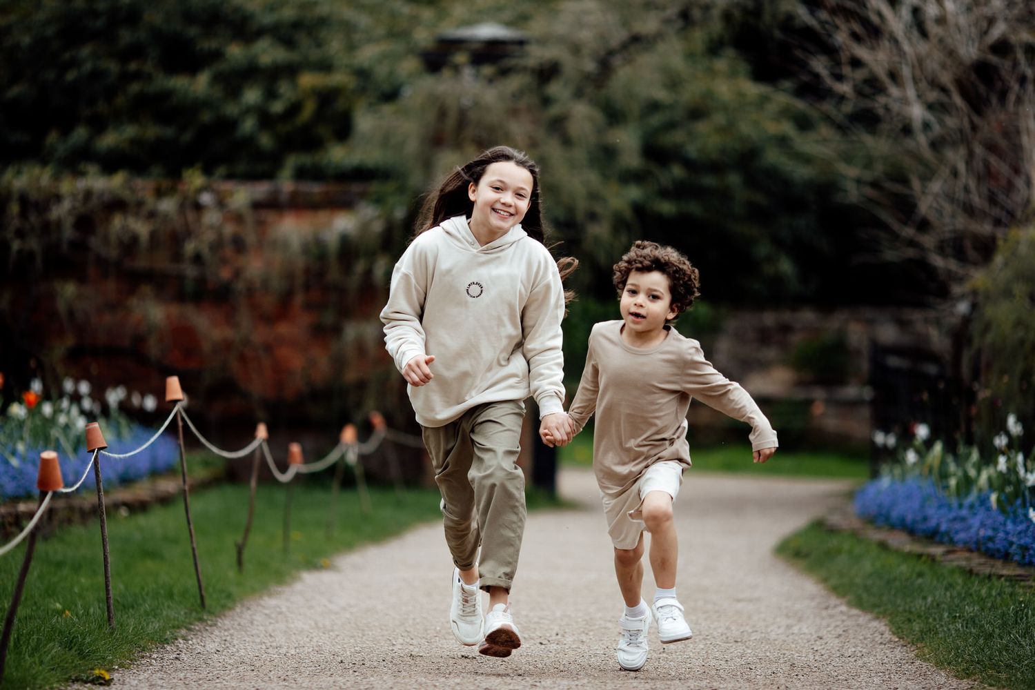 A playful outdoor photo session captures movement and joy along a garden path.