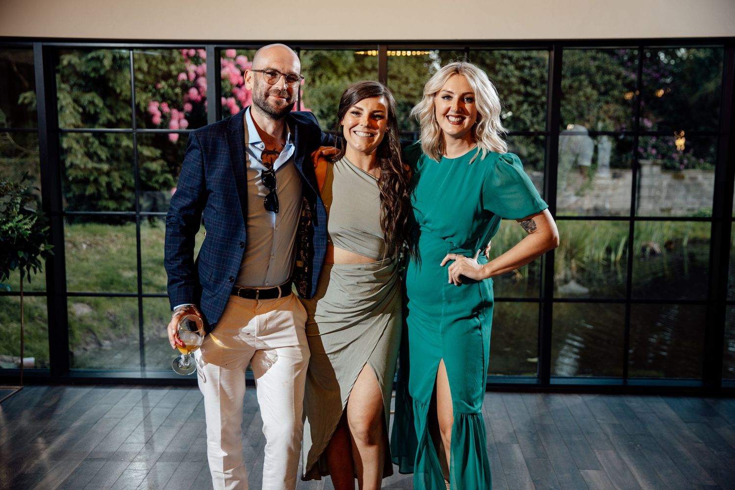 Wedding guests mingling in a modern venue with large glass windows.