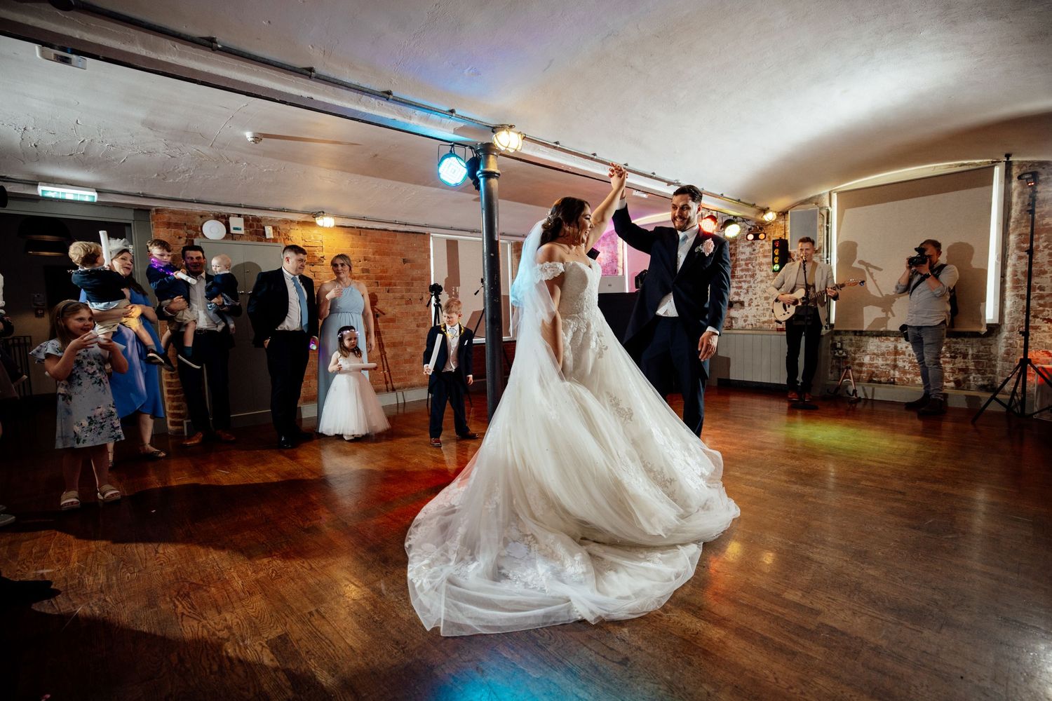 Wedding couple dancing on wooden floor during reception celebration.