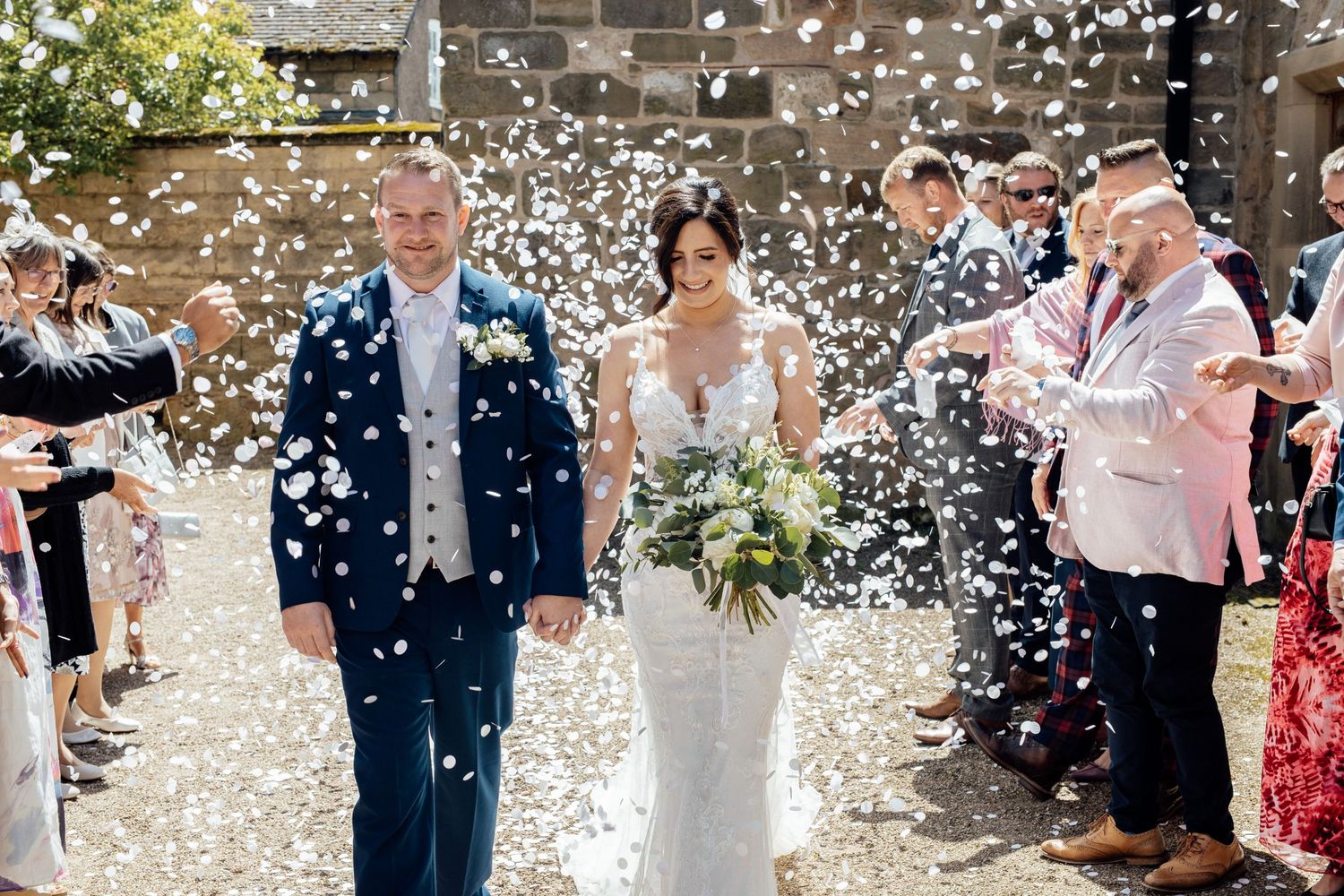 Wedding celebration with guests throwing white confetti in the air.