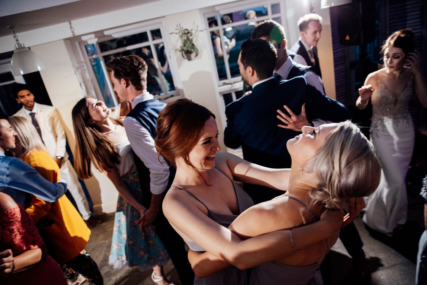 Lively dance floor scene at wedding reception with guests celebrating.