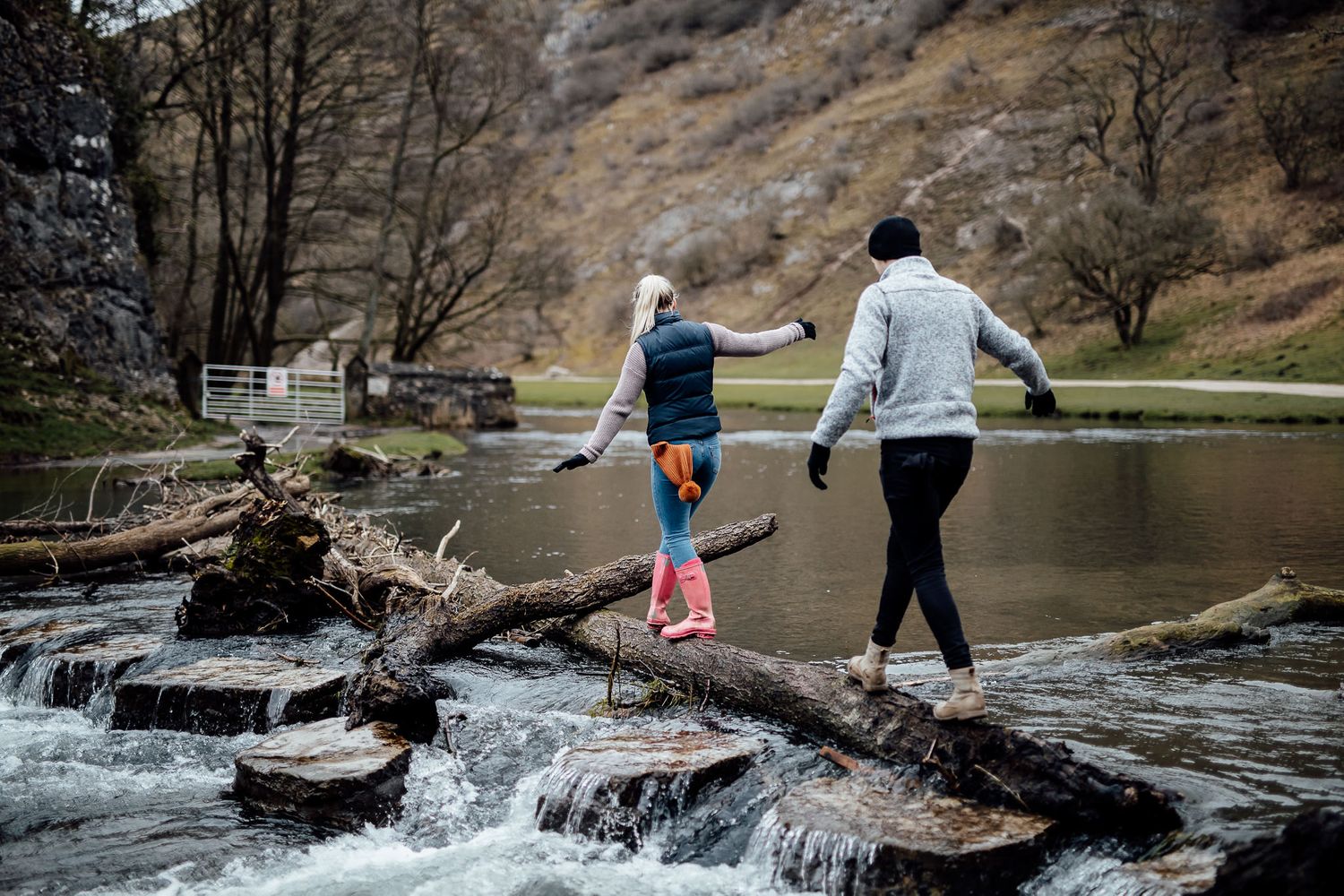 Adventure seekers balance together while crossing a natural waterfall dam.