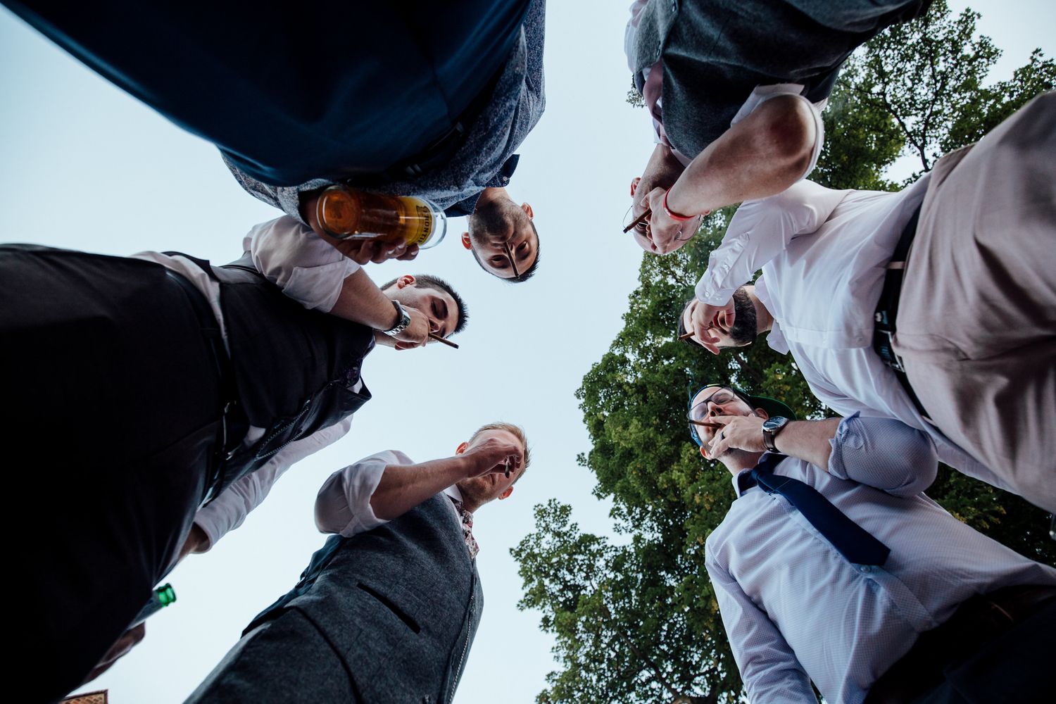 Low angle view of wedding guests mingling outdoors against blue sky.