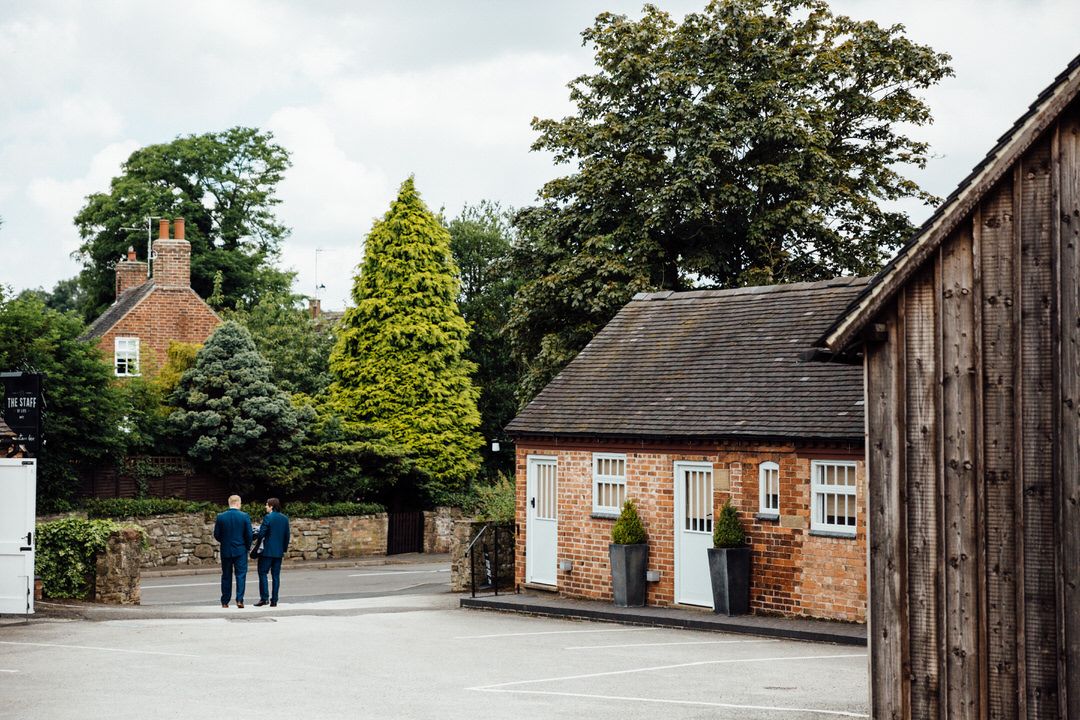 View of traditional brick buildings and courtyard at a rustic wedding venue.