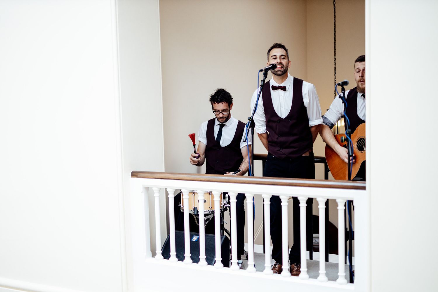 Musicians in formal attire performing from a white balcony railing.