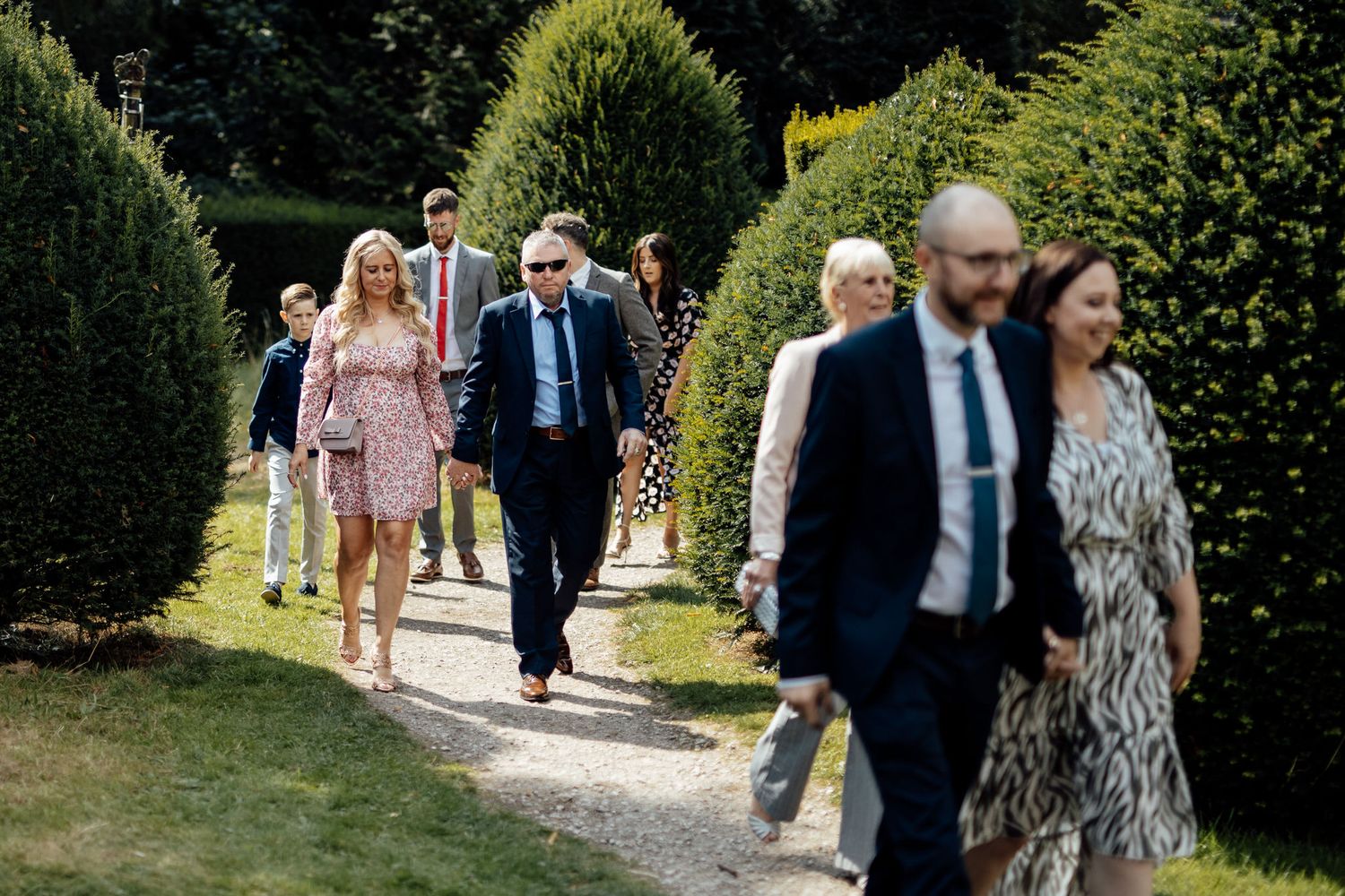 Wedding guests mingle on a manicured lawn during an outdoor garden reception.