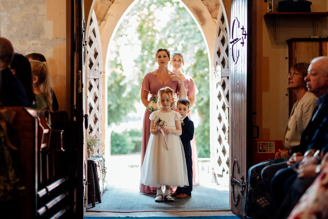 Stone archway frames wedding ceremony entrance with natural lighting streaming through.