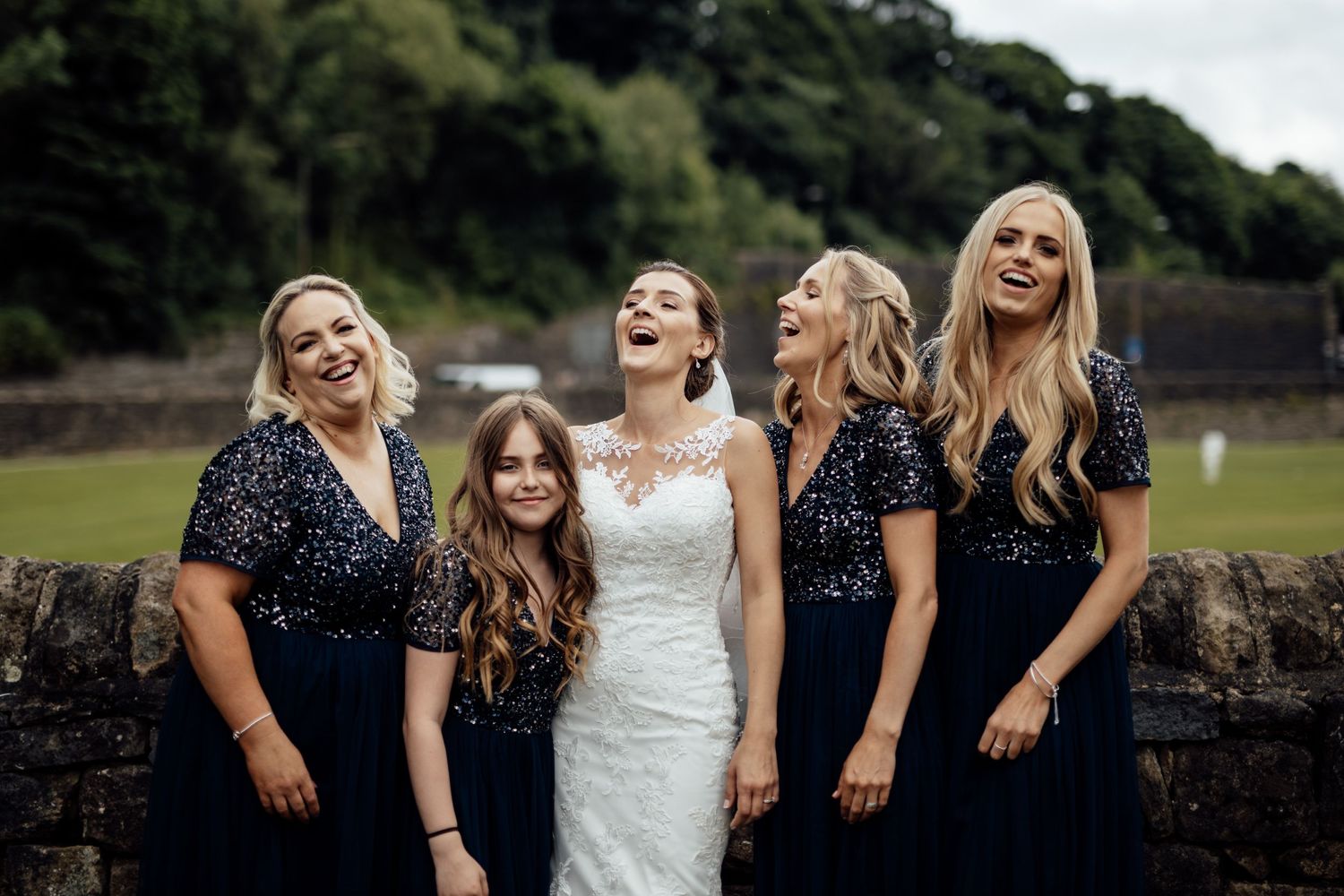 A group of women in navy blue dresses share a joyful moment outdoors.