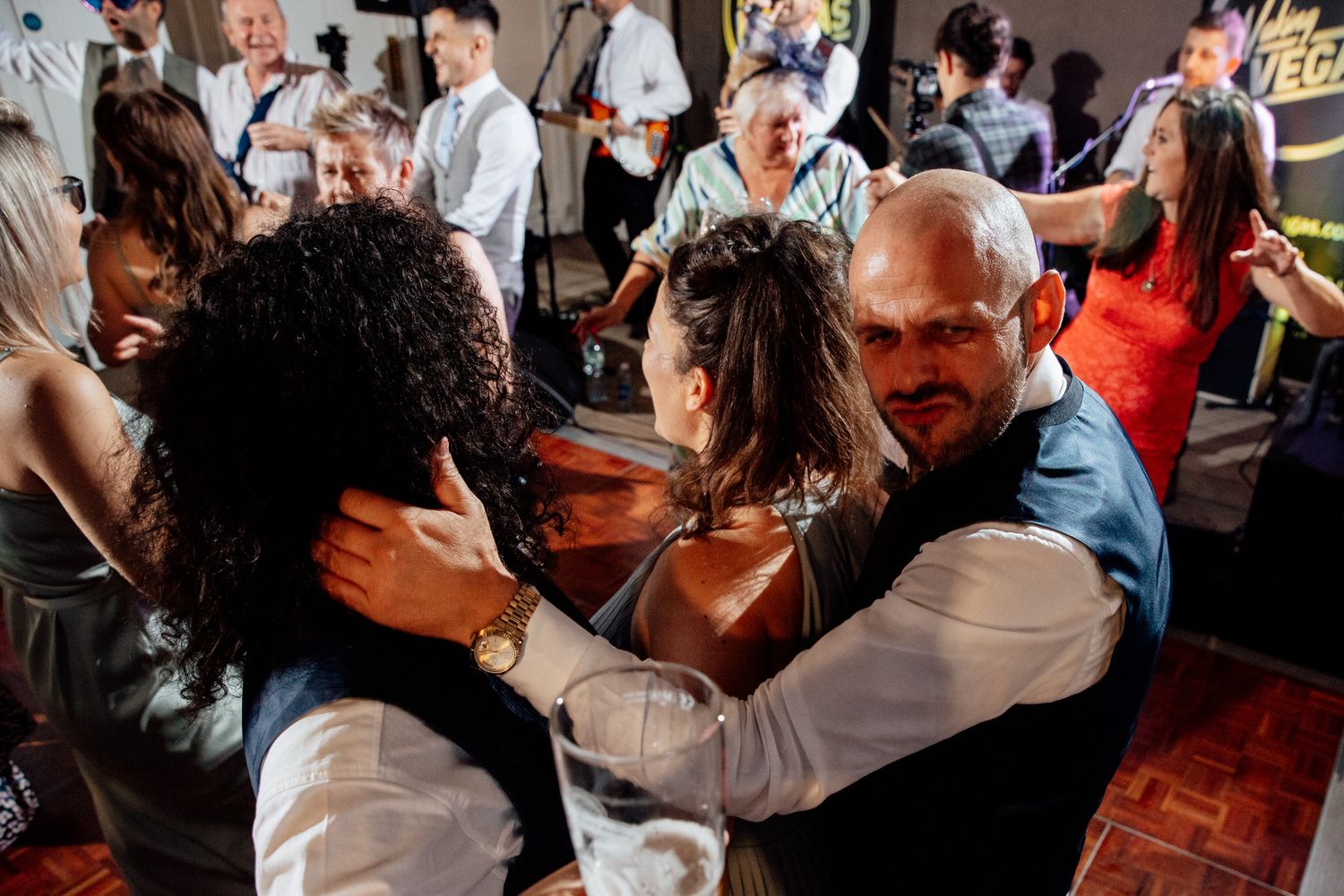 Wedding guests enjoying themselves on a crowded dance floor during an evening celebration.